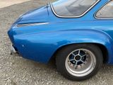 a blue car that is parked on the gravel
