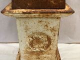 an antique cast iron urn with a rusted finish and a wooden base