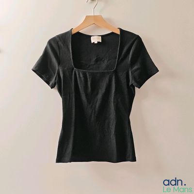 une chemise noire accrochée au mur à côté d'un cintre en bois