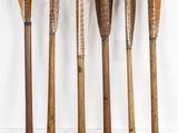 six wooden arrows are lined up against a white wall