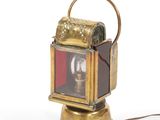 a small brass lantern with a red light on it
