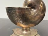 an antique silver bowl on a stand on a black table