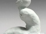 a white sculpture of a man sitting on a rock