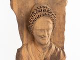 carved head of a woman with a crown on a piece of wood
