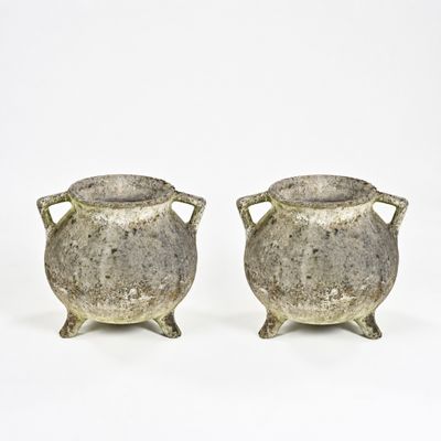 paire de vases en argent munis d'anses, posés sur des socles, sur fond blanc