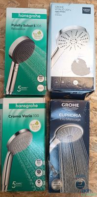 trois pommeaux de douche Grohe dans leur emballage, posés sur une surface en bois