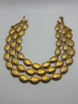a gold necklace with three rows of leaves on a white background