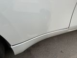 the side of a white car with a denting dent