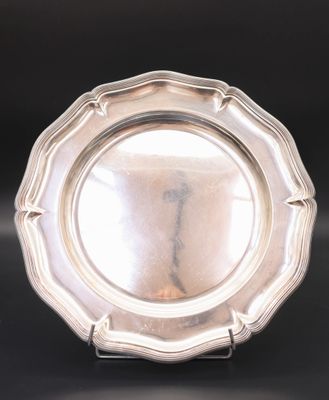 a silver plate on a stand on a black surface