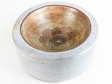 a small bowl with a flower on it on a white surface