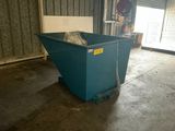 a blue dumpster sitting in a garage with a door open