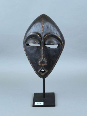 image d'un masque en bois sur un support sur fond blanc