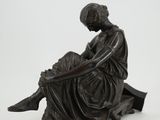 statue of a woman sitting on a bench with her legs crossed