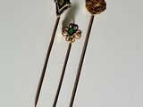 three small metal pins with a gold and green design