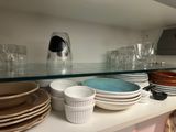 many plates and cups on the shelf in the kitchen