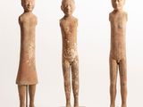 three figurines of a man and a woman standing on wooden bases