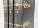 trois livres noirs aux tranches dorées sont empilés les uns sur les autres
