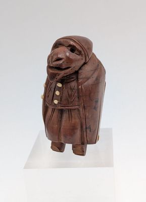 sculpture of a woman in a brown coat and scarf on a white pedestal