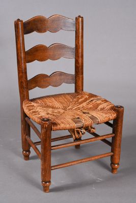 an old wooden chair with a woven seat on a gray background