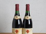 deux bouteilles de vin posées sur une table en bois, à côté d'une bouteille de vin