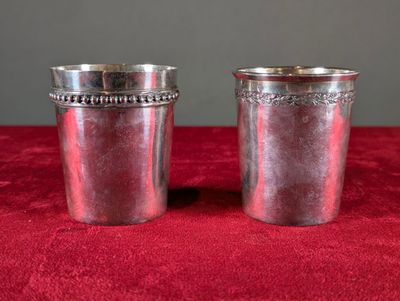 deux tasses en argent posées sur une nappe rouge