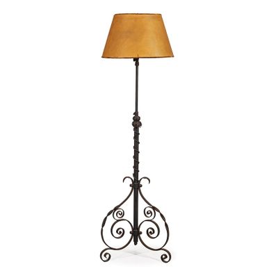 une grande lampe en fer surmontée d'un abat-jour marron