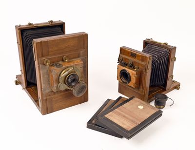 two old cameras are sitting next to each other on a white surface