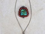 a close up of a necklace and a pendant on a white surface