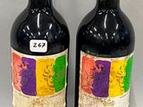 two bottles of red wine sitting next to each other on a table