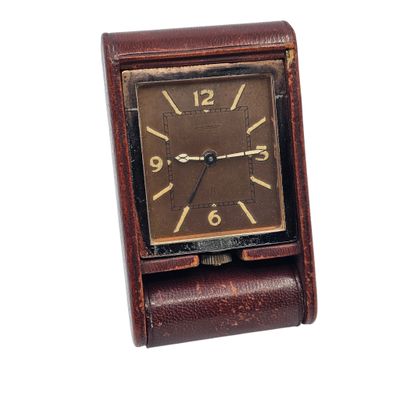 a small clock that is sitting on top of a leather case