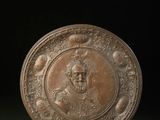 une grande plaque en bronze sur laquelle est représentée la tête d'un homme
