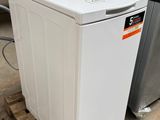 une machine à laver blanche posée sur une palette dans un entrepôt