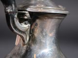 a silver vase that has a handle on it