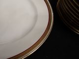 a white plate with a gold rim and a stack of gold plates