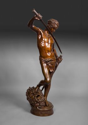 une statue en bronze représentant un homme tenant une épée, debout sur un rocher