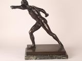 statue en bronze représentant un homme lançant un frisbee, posée sur un socle en marbre