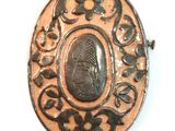 an oval metal object with a picture of a woman on it