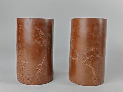 deux vases marron ornés d'oiseaux et de fleurs, posés sur une table