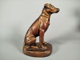 bronze statue of a dog sitting on top of a wooden base