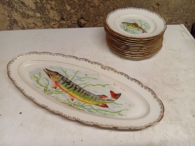 a plate with a fish painted on it next to a stack of plates