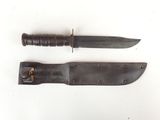 pair of knives with leather sheaths on a white surface