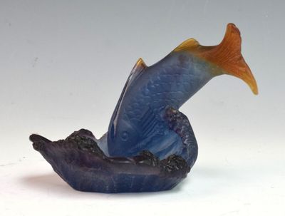 une figurine de poisson bleue et orange posée sur le toit d'un bateau