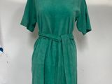 a green dress on a mannequin stand in front of a white backdrop