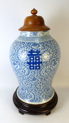 un vase bleu et blanc muni d'un couvercle en bois, posé sur un socle