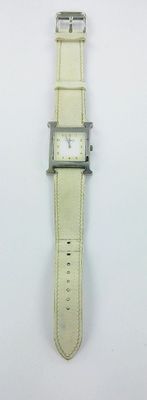 un gros plan d'une montre sur une surface blanche avec un fond blanc