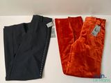 two pairs of orange and black pants sitting on top of a white table
