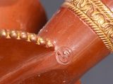 a close up of a brown vase with a gold decoration on it