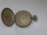 a silver pocket watch sitting on a white surface