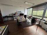 a room with a desk, chairs, and a large window