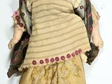 an old doll with a brown outfit and a hat on a white surface